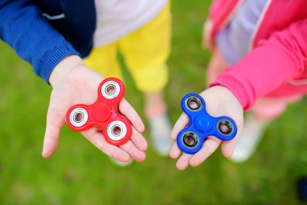 Manos de las niñas jugando con los hilanderos fidget — Foto de Stock