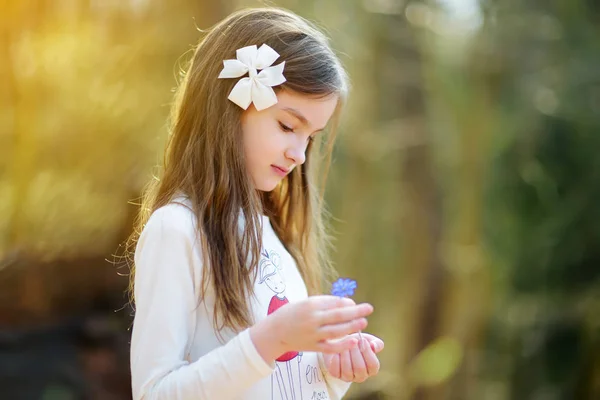 Girl picking first flower in forest — Stock Photo, Image