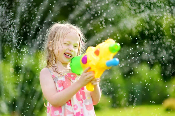 Criança engraçada brincando com arma de água — Fotografia de Stock