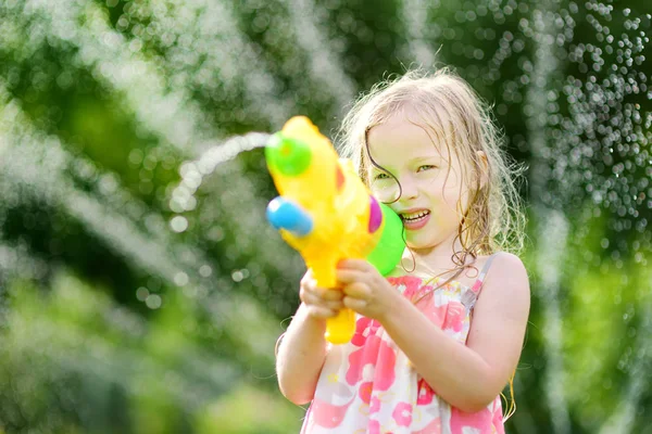 Забавный ребенок, играющий с водяным пистолетом — стоковое фото