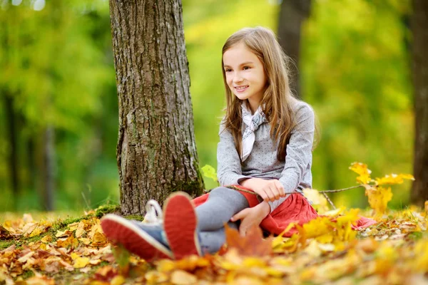Flicka sitter på bladverk i park — Stockfoto