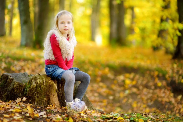 Menina sentada no toco no parque — Fotografia de Stock