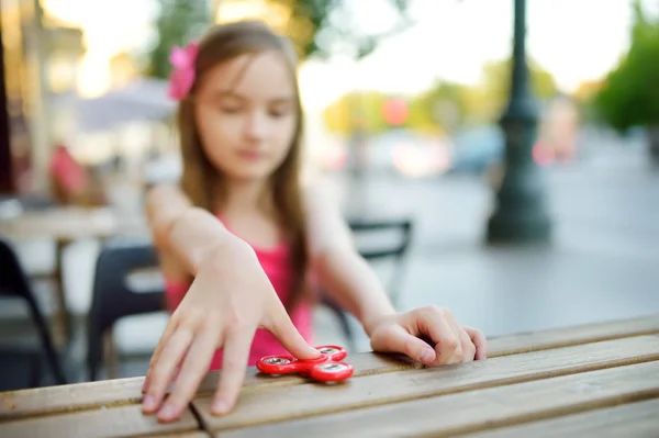 Girl playing with colorful fidget spinner — Stock Photo, Image