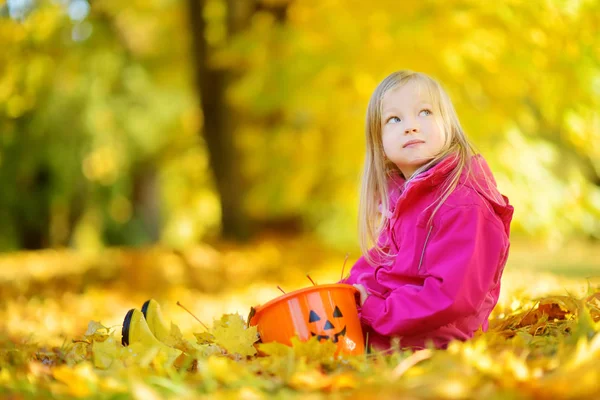 Fille assise sur le feuillage dans le parc — Photo