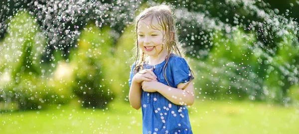 Küçük kız yağmurlama ile oynamak — Stok fotoğraf