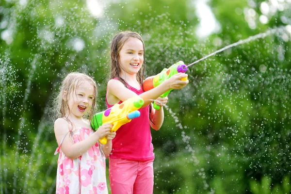 Su silahlarla oynayan küçük kızlar — Stok fotoğraf
