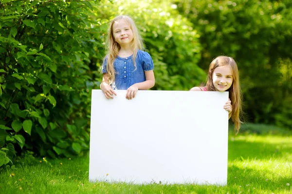 Little sisters boş beyaz tahta holding — Stok fotoğraf