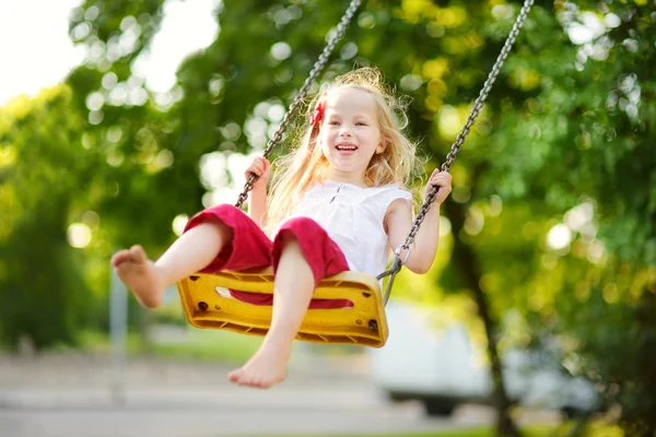 Little girl swinging on playground — Stock Photo, Image