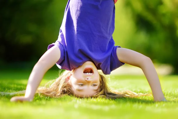 Menina jogar cabeça sobre saltos na grama — Fotografia de Stock