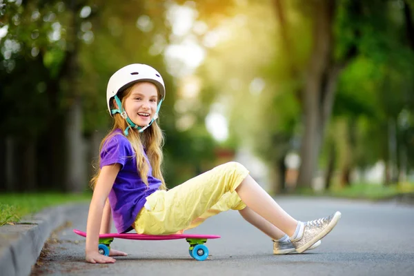 Маленькая девочка учится кататься на скейтборде в парке — стоковое фото