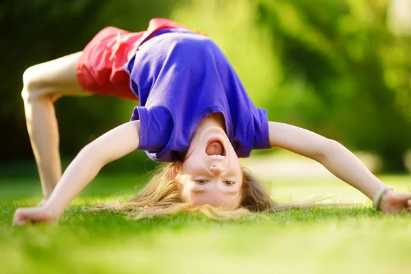 Meisje hals over kop spelen op gras — Stockfoto