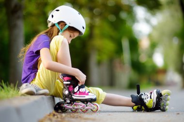 Küçük kız paten kaymayı öğreniyor. 