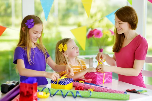 Kleine Schwestern und Mutter wickeln Geschenke ein — Stockfoto