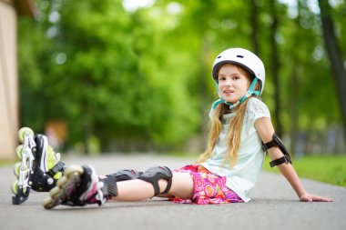 Küçük kız paten kaymayı öğreniyor. 