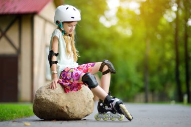 Küçük kız paten kaymayı öğreniyor. 