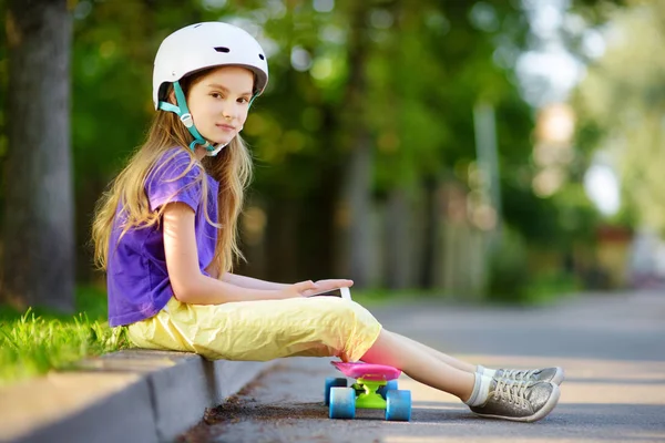 Маленькая девочка учится кататься на скейтборде в парке — стоковое фото