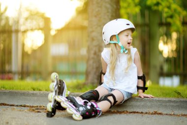 Küçük kız paten kaymayı öğreniyor. 