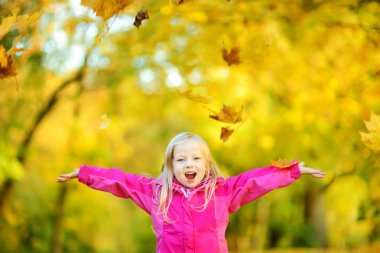 sonbahar yaprakları ile oynarken küçük kız 