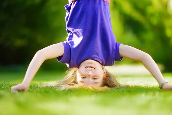 Meisje hals over kop spelen op gras — Stockfoto