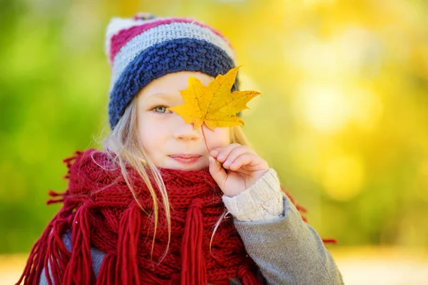 Маленькая девочка играет с осенним листом — стоковое фото