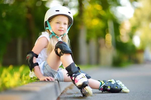 Küçük kız paten kaymayı öğreniyor. 