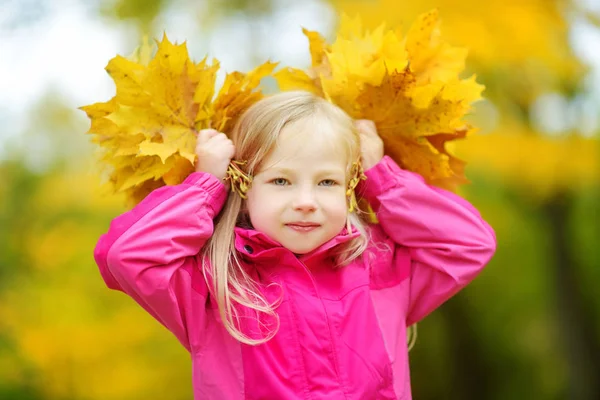 sonbahar yaprakları ile oynarken küçük kız 