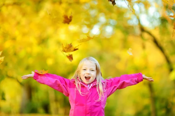 Kleines Mädchen spielt mit Herbstblättern — Stockfoto