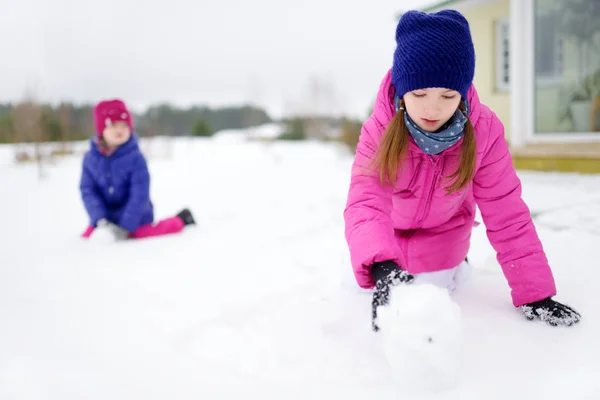 Två små flickor leker med snö — Stockfoto