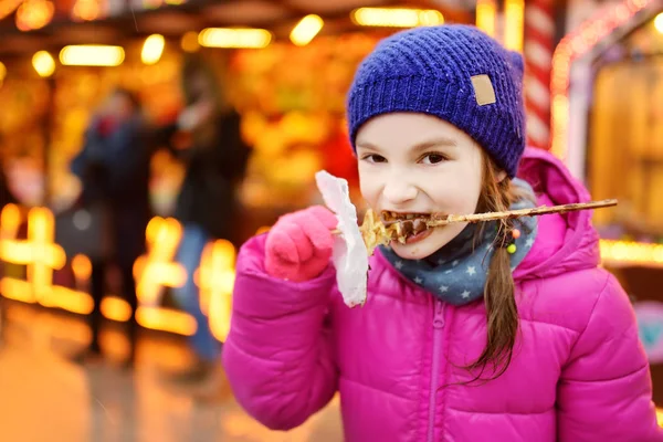 Girl eating waffle at Christmas market — Stock Photo, Image