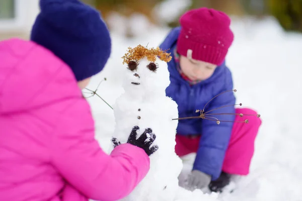 Two little girls making snowman — Stock Photo, Image