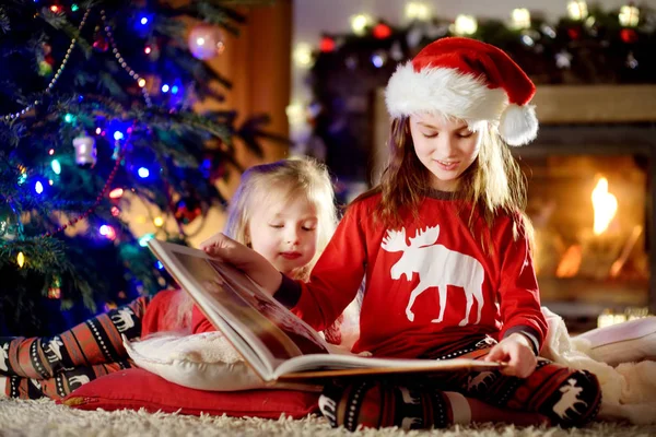 Systrarna läser bok på jul — Stockfoto