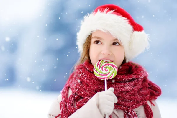 Flicka klädd Santa mössa med lollipop — Stockfoto