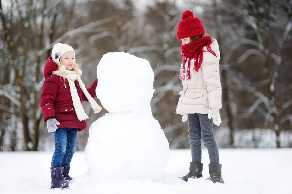 Twee kleine meisjes maken sneeuwpop — Stockfoto