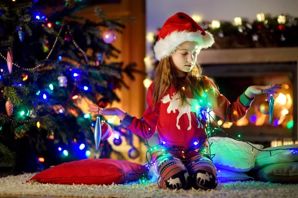 Dívka s elektrickým věnec u vánočního stromu — Stock fotografie