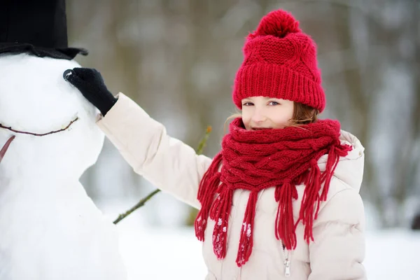 Adorable niña construyendo un muñeco de nieve —  Fotos de Stock