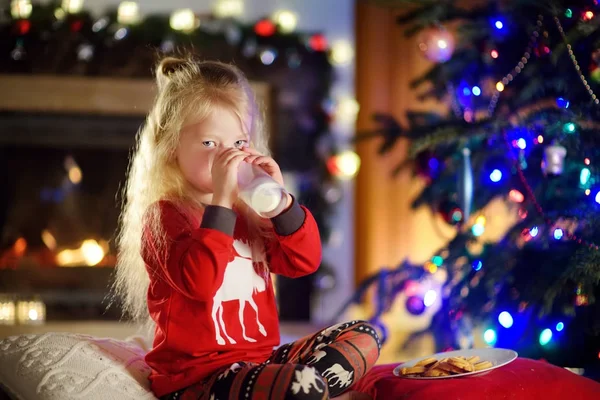 Fille ayant du lait et des biscuits près d'une cheminée — Photo