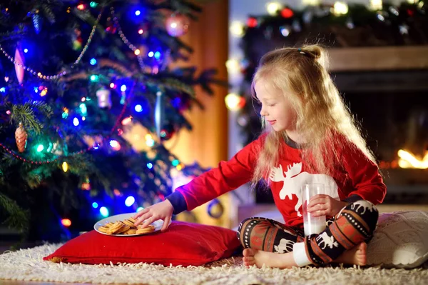 Girl having milk and cookies by a fireplace — Stock Photo, Image