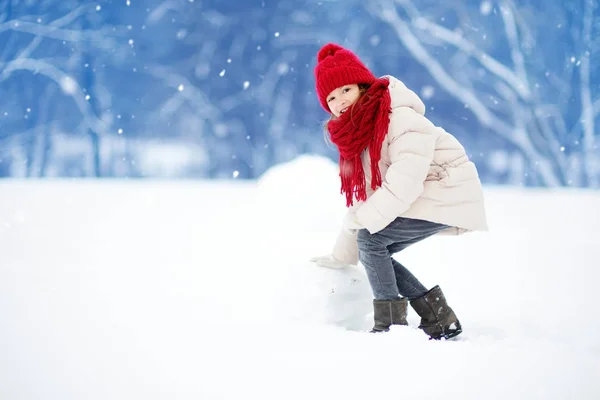 Meisje gebouw een sneeuwpop — Stockfoto