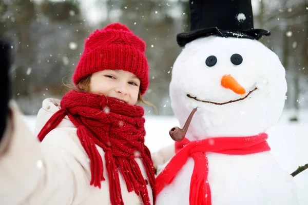 Niña construyendo un muñeco de nieve —  Fotos de Stock