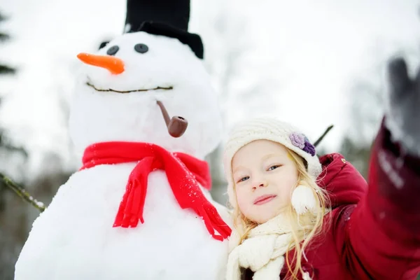 Menina construindo um boneco de neve — Fotografia de Stock