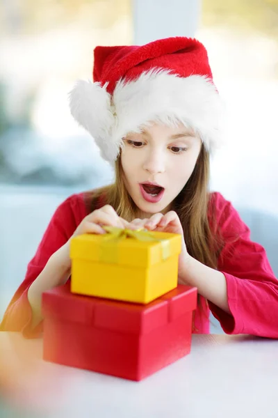 Κοπέλα φορώντας καπέλο Santa άνοιγμα συσκευασία δώρου — Φωτογραφία Αρχείου
