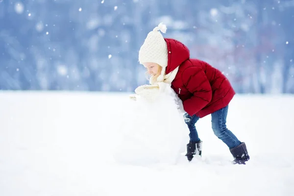 Malá dívka stavět sněhuláka — Stock fotografie