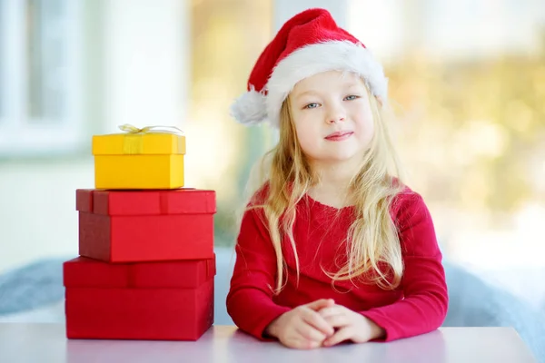 Menina em chapéu de Santa com presentes — Fotografia de Stock