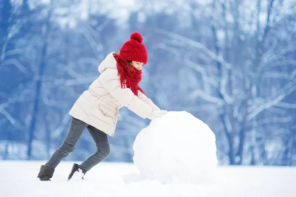 Klein meisje bouwen van een sneeuwpop — Stockfoto