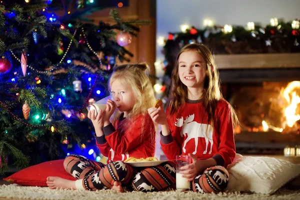 Soeurs ayant du lait et des biscuits près d'une cheminée — Photo