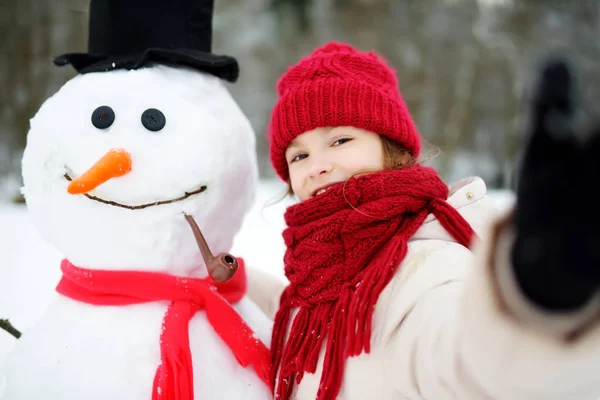 Niña construyendo un muñeco de nieve — Foto de Stock