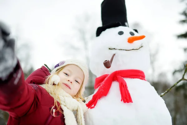 Adorável menina edifício boneco de neve — Fotografia de Stock