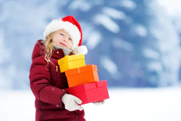 Дівчина в капелюсі Санта тримає різдвяні подарунки — стокове фото