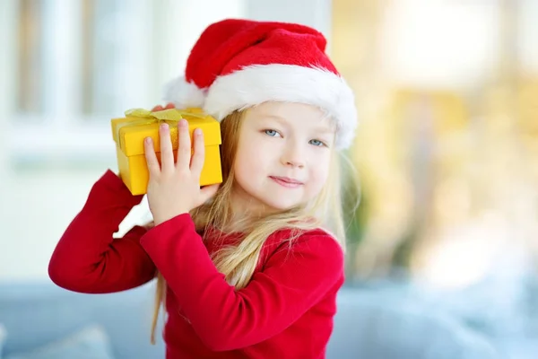 Дівчина в капелюсі Санта відкриває подарункову коробку — стокове фото