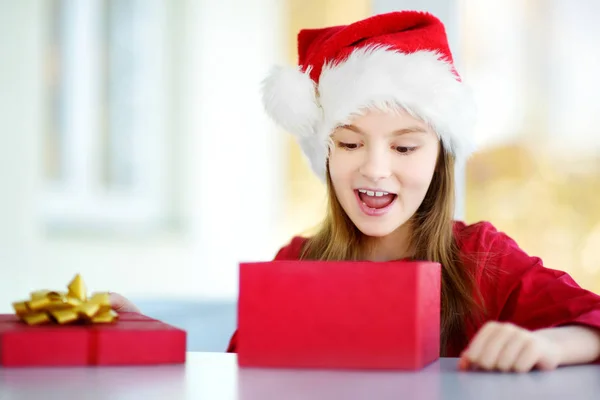 Niña con sombrero de Santa abrir una caja de regalo —  Fotos de Stock